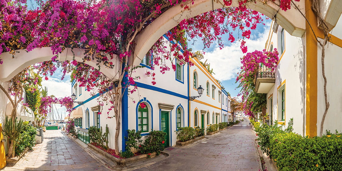 Whitewashed houses on a street in Puerto de Mogan, festooned with Bougainvillea flowers
